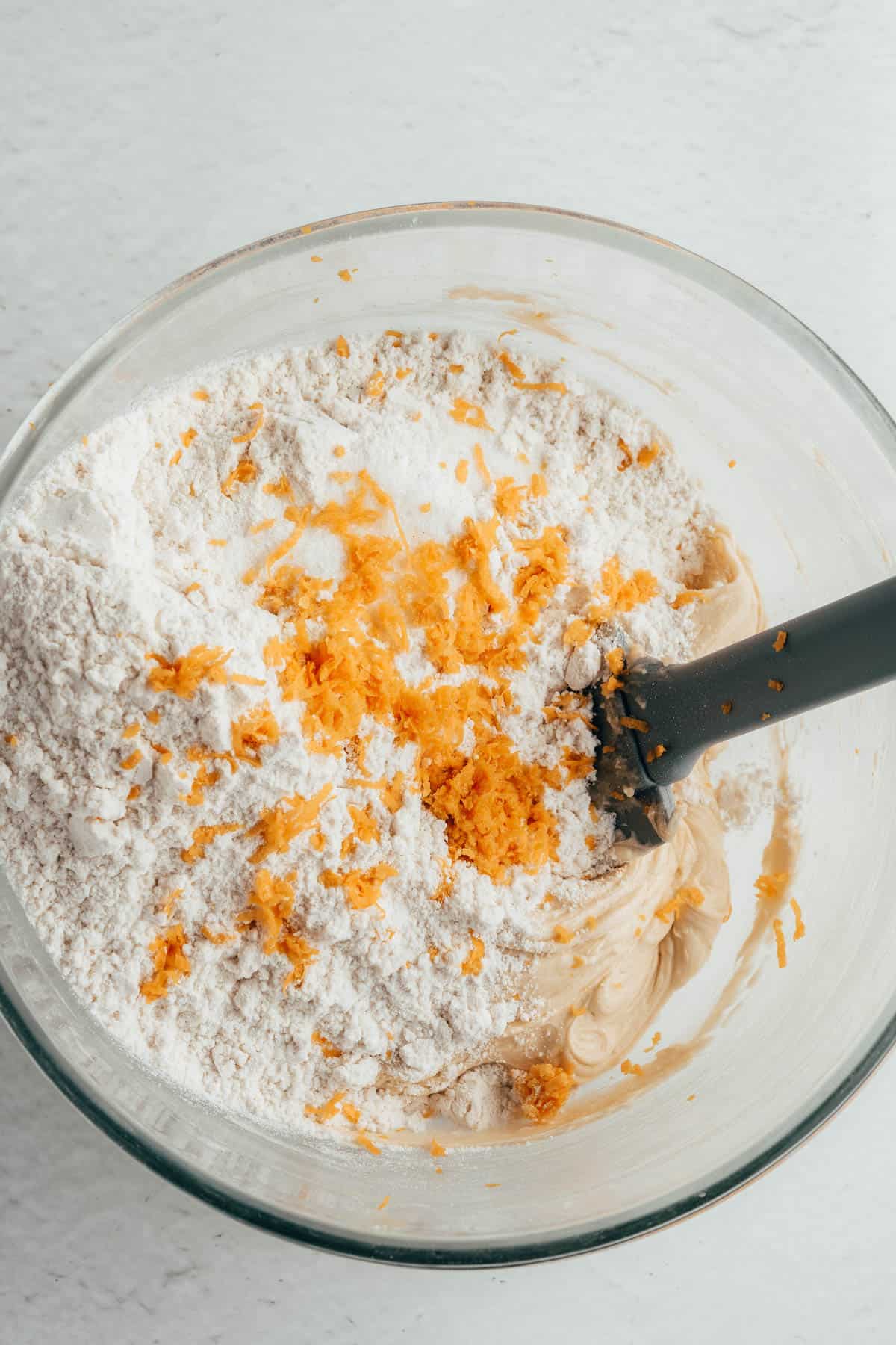 Adding flour and orange zest to shortbread cookie dough.