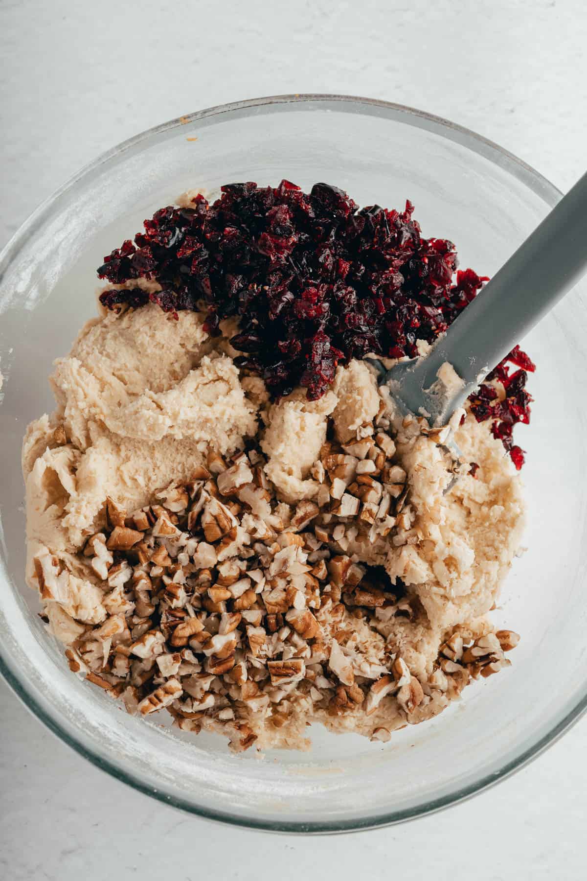 Adding chopped pecans and cranberries to shortbread cookie dough.