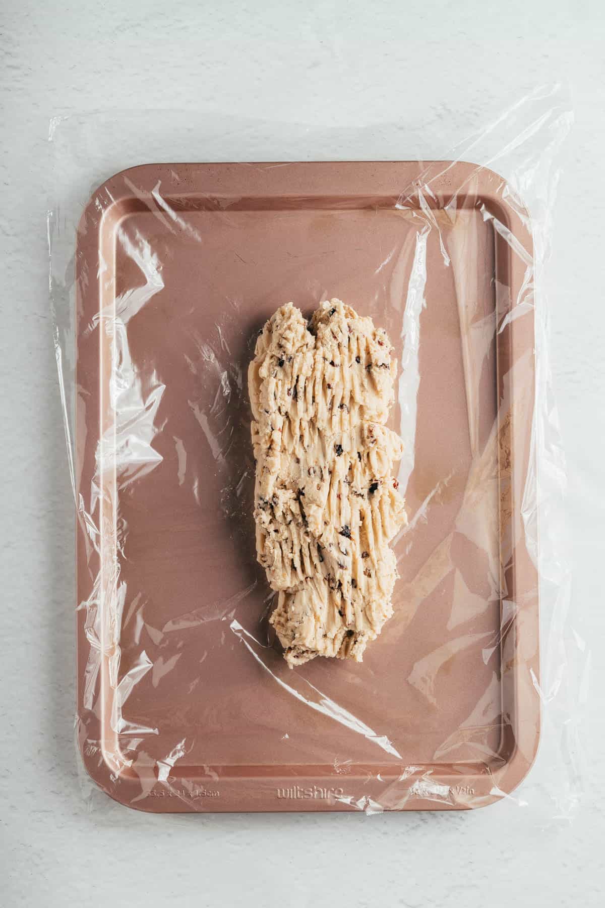 Spreading shortbread dough on plastic wrap.