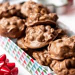 Homemade crockpot candy peanut clusters in a decorative holiday tin.