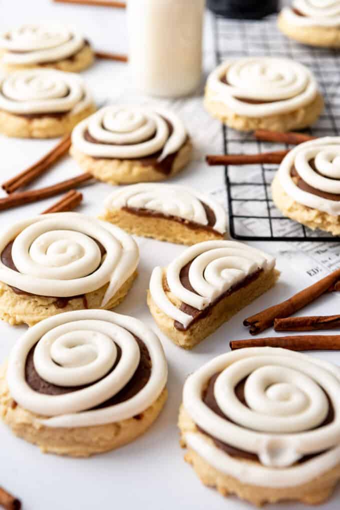 Crumbl Cookie copycat cinnamon roll cookies scattered with some cinnamon sticks between them.