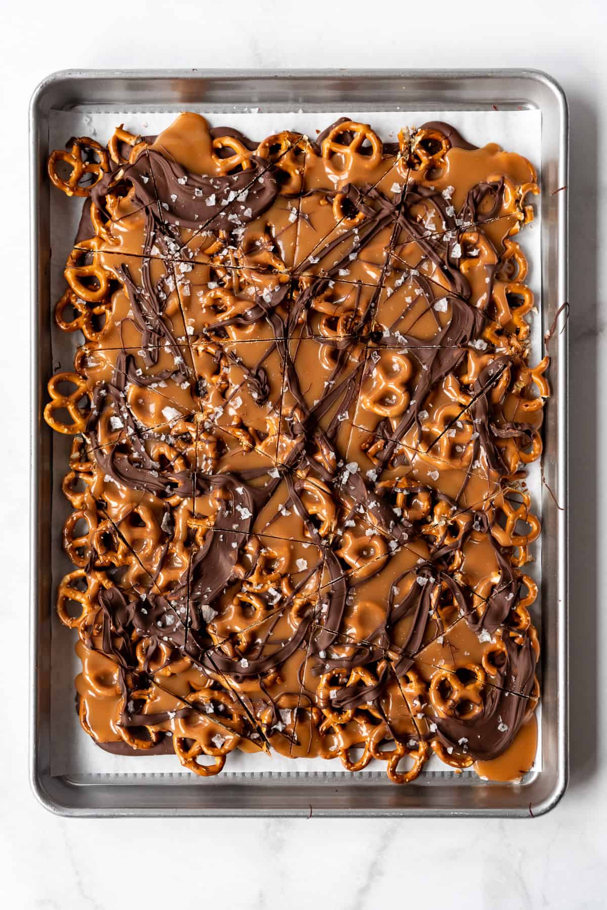 A baking sheet with set up homemade pretzel caramel chocolate candy on it.