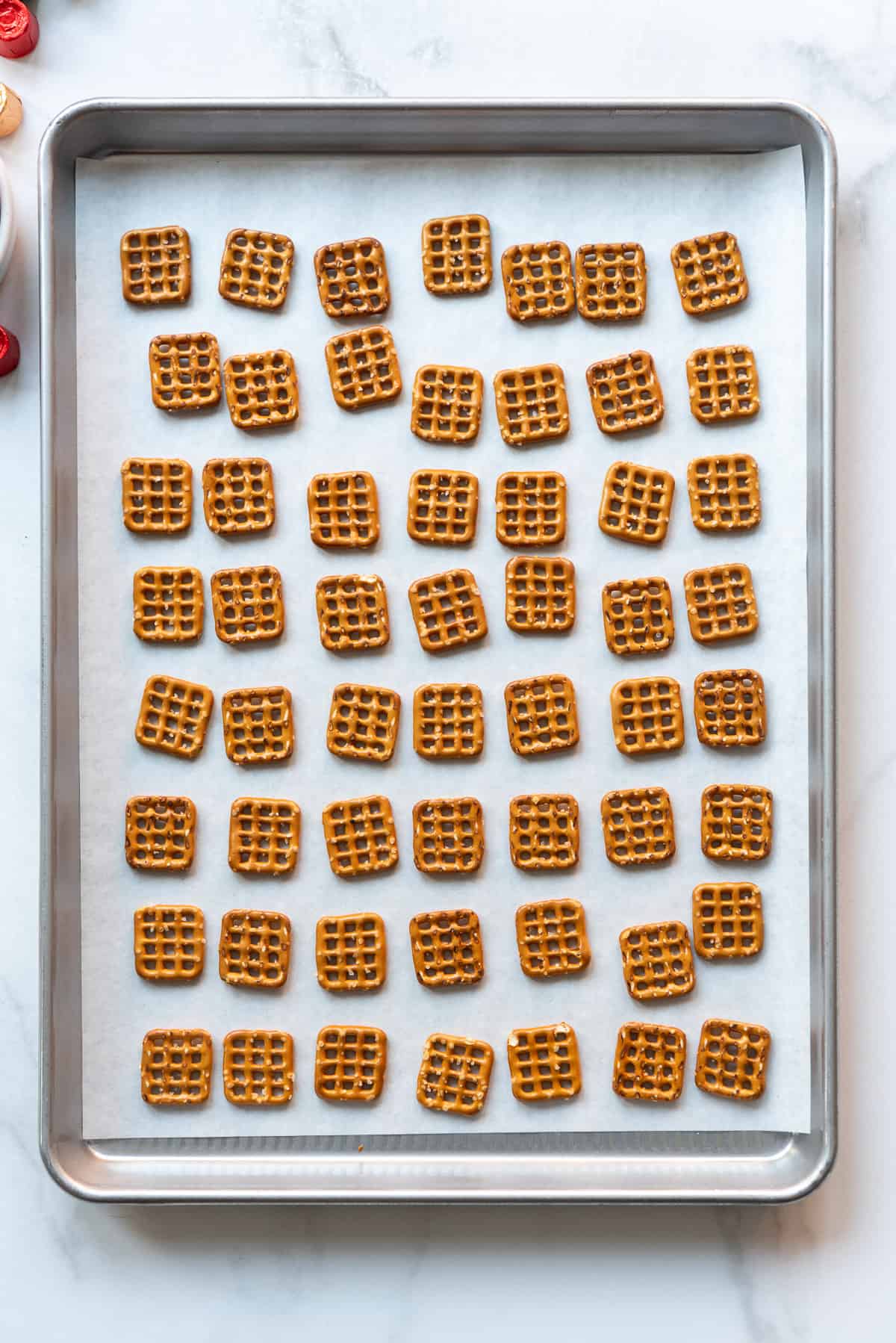 Square pretzels arranged on a baking sheet lined with parchment paper.