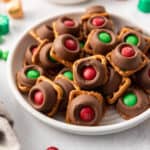 A square image of a plateful of Rolo pretzels with red and green Christmas M&Ms.