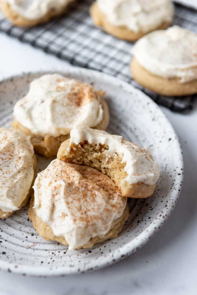 Soft eggnog cookies on a plate with a bite taken out of one of them.