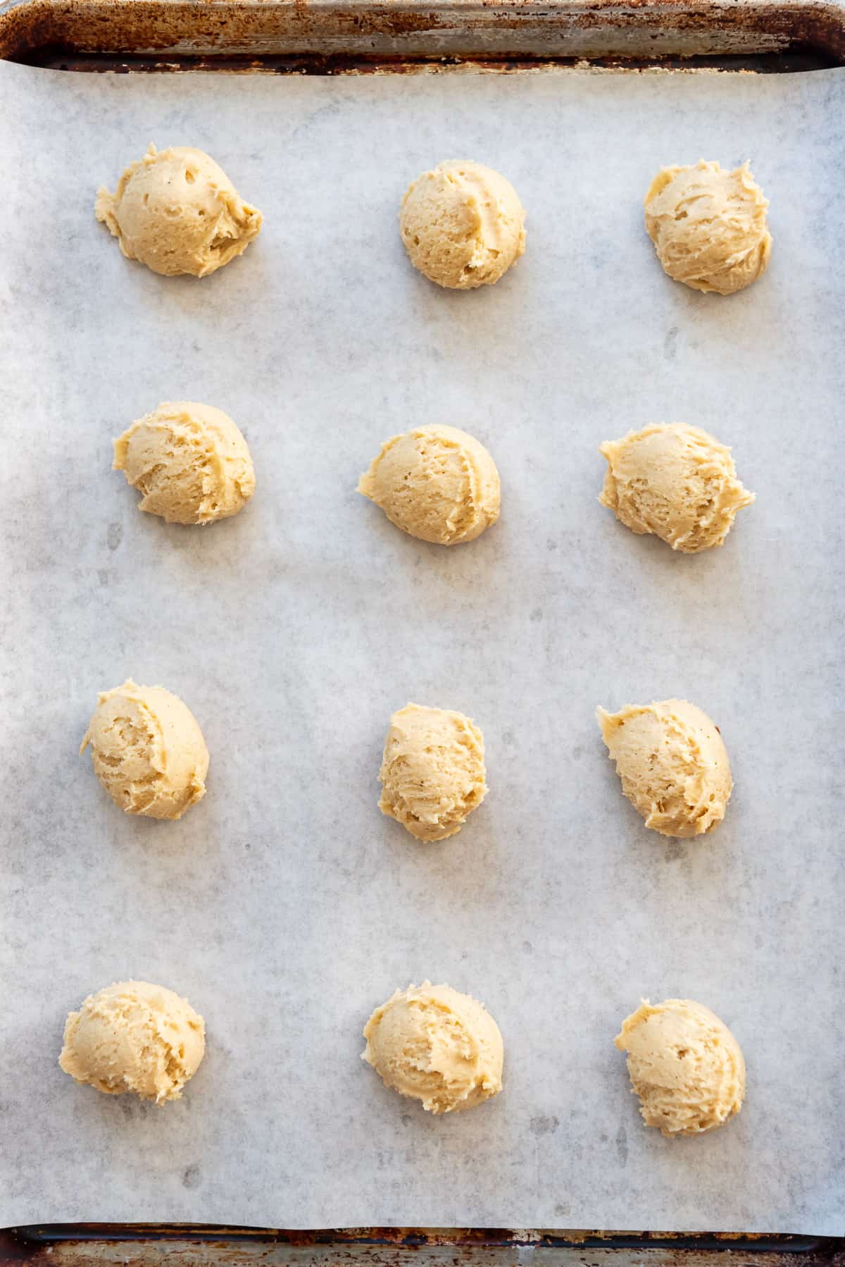 Balls of eggnog cookie dough on parchment paper.