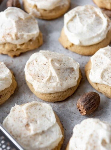 Frosted eggnog cookies on a baking sheet lined with parchment paper.