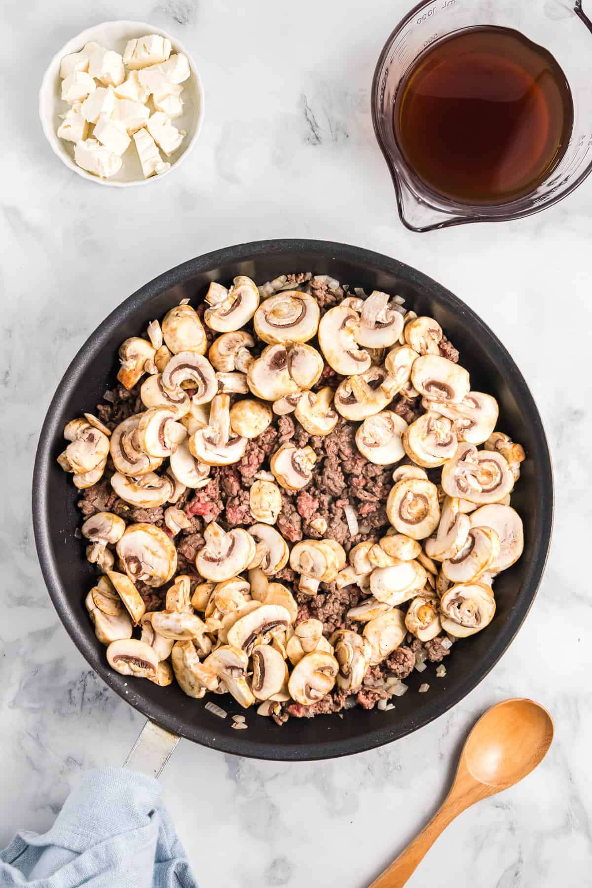 Adding sliced mushrooms to ground beef.