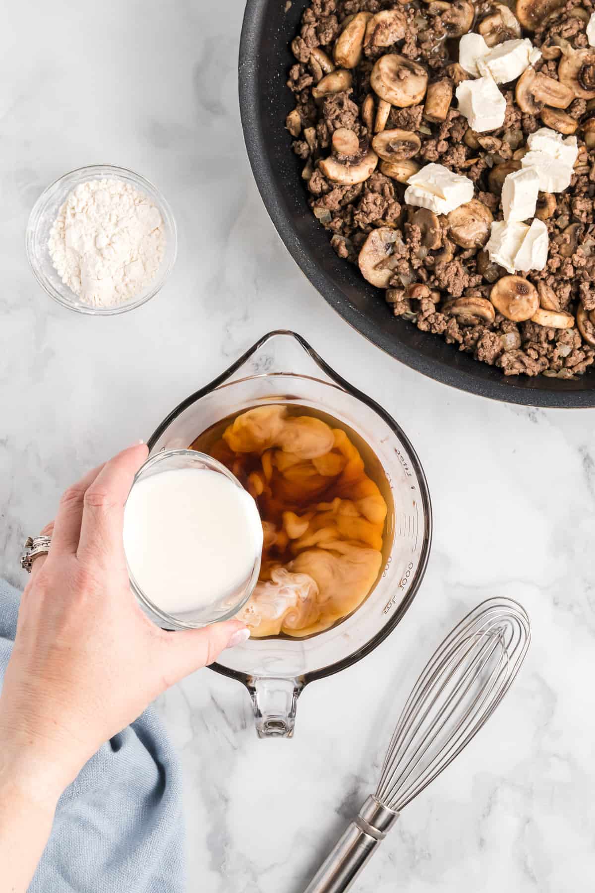 Adding milk to beef broth.