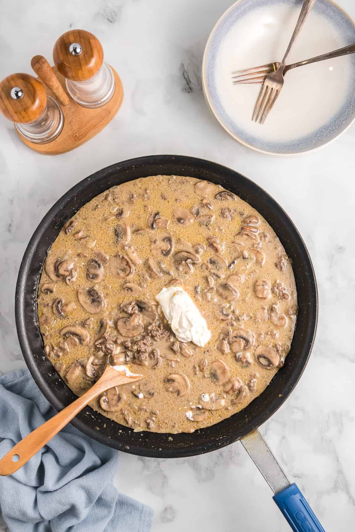 Adding sour cream to ground beef stroganoff.