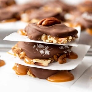 Stacked homemade turtles with caramel, pecans, and chocolate.