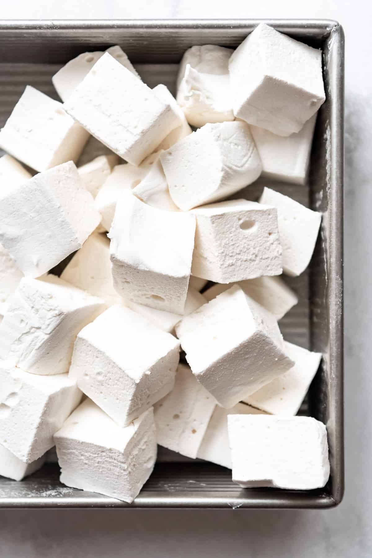 Fluffy homemade vanilla marshmallows piled in a metal pan.