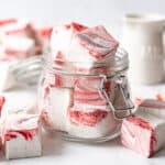 A glass jar filled with homemade peppermint marshmallow cubes.