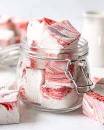 A glass jar filled with homemade peppermint marshmallow cubes.