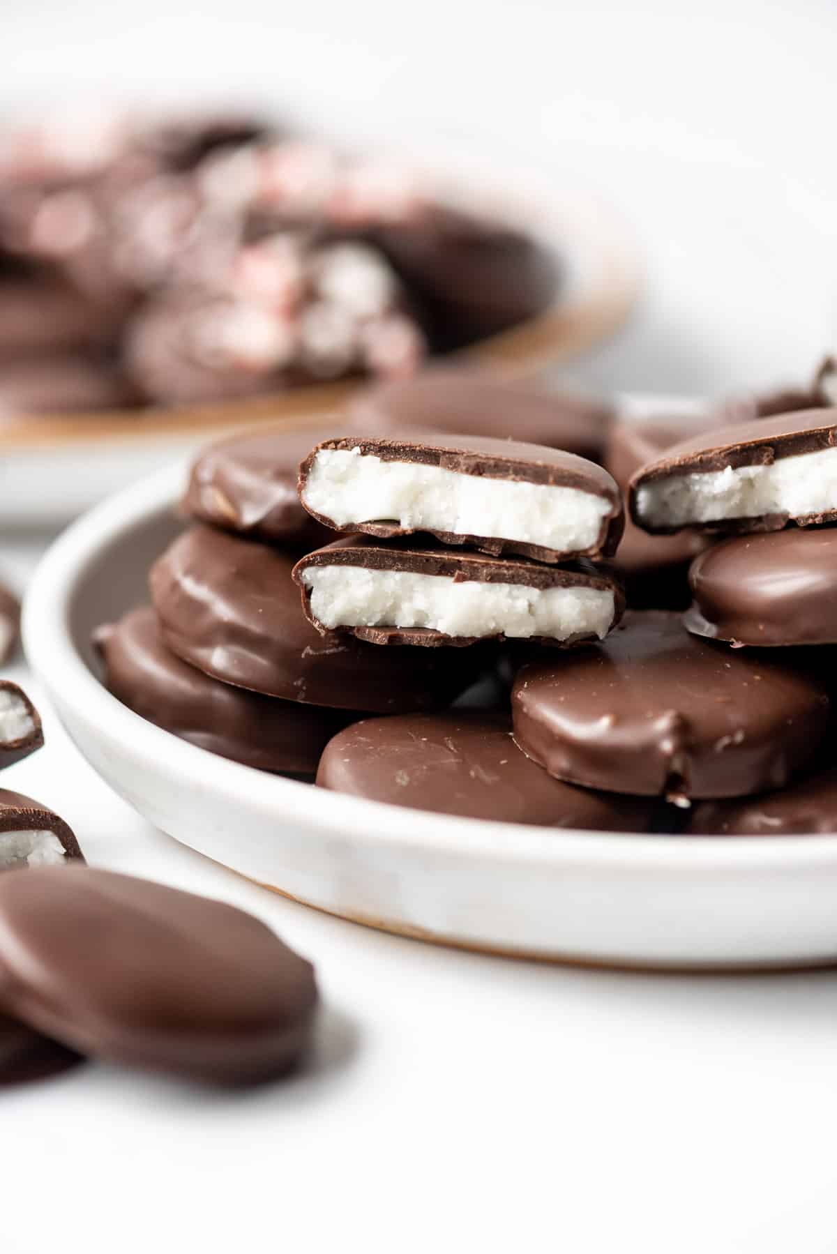 A homemade peppermint patty broken in half to reveal the creamy white mint interior.