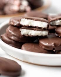 Homemade peppermint patties candies stacked on a plate.