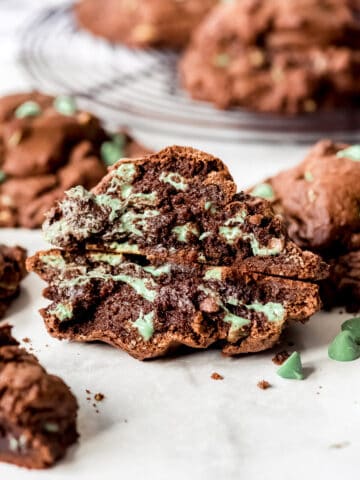 A mint chocolate chip cookie that has been broken in half to show the gooey insides.