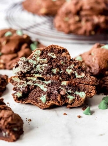 A mint chocolate chip cookie that has been broken in half to show the gooey insides.