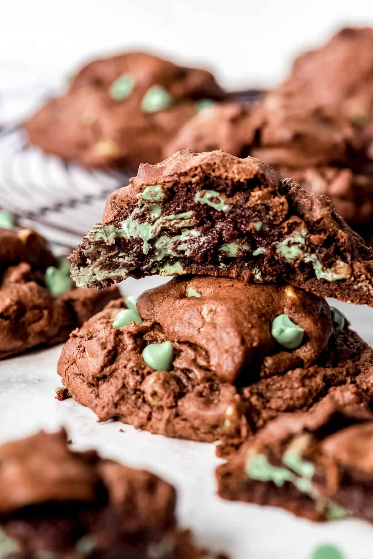 Dark chocolate cookies with green mint chips stacked on top of each other.
