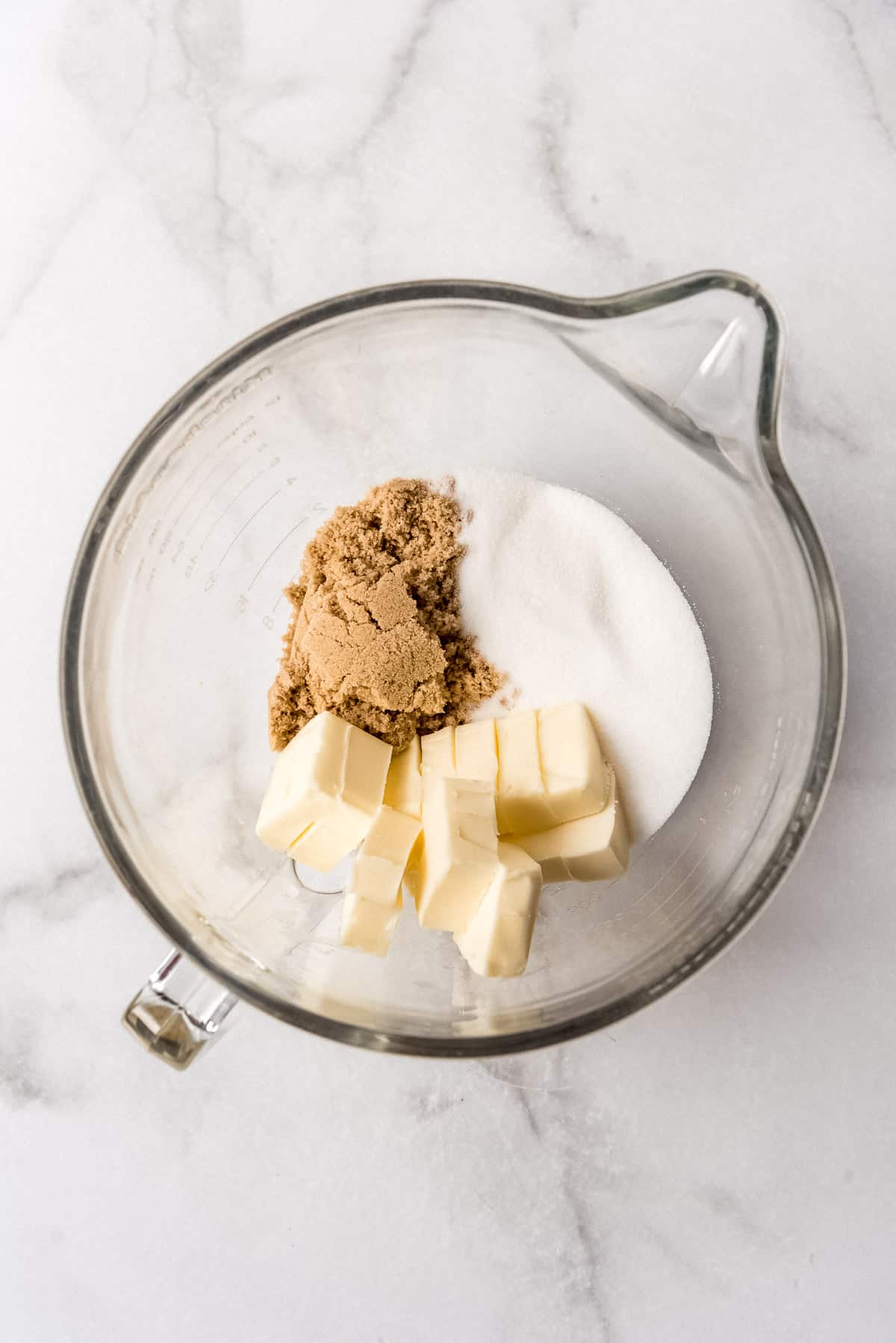 Butter, brown sugar, and granulated sugar in a glass bowl.