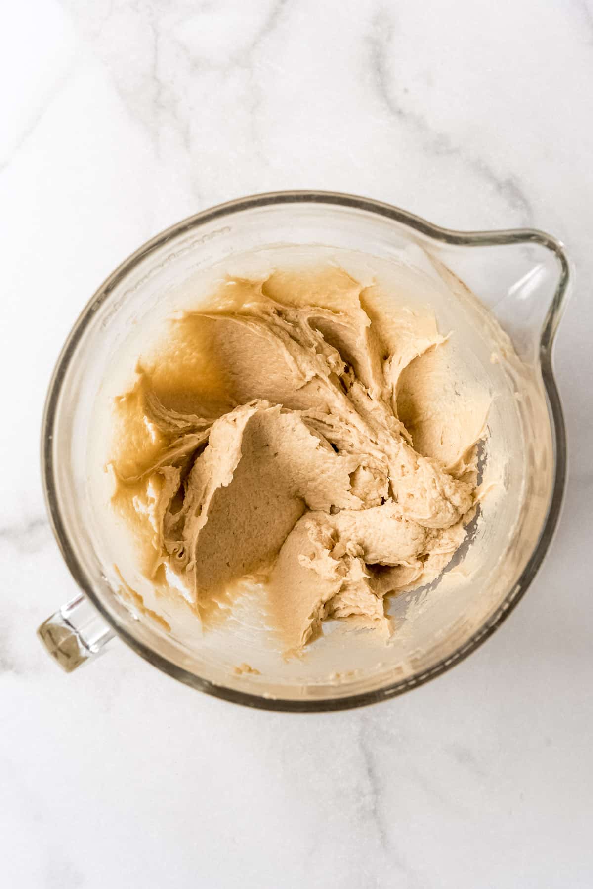 Creamed butter, sugar, vanilla, and eggs in a glass bowl.