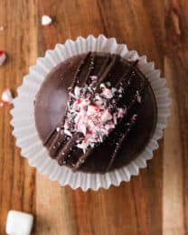 A hot cocoa bomb decorated with crushed peppermint candy canes on top.