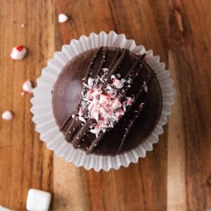 A hot cocoa bomb decorated with crushed peppermint candy canes on top.