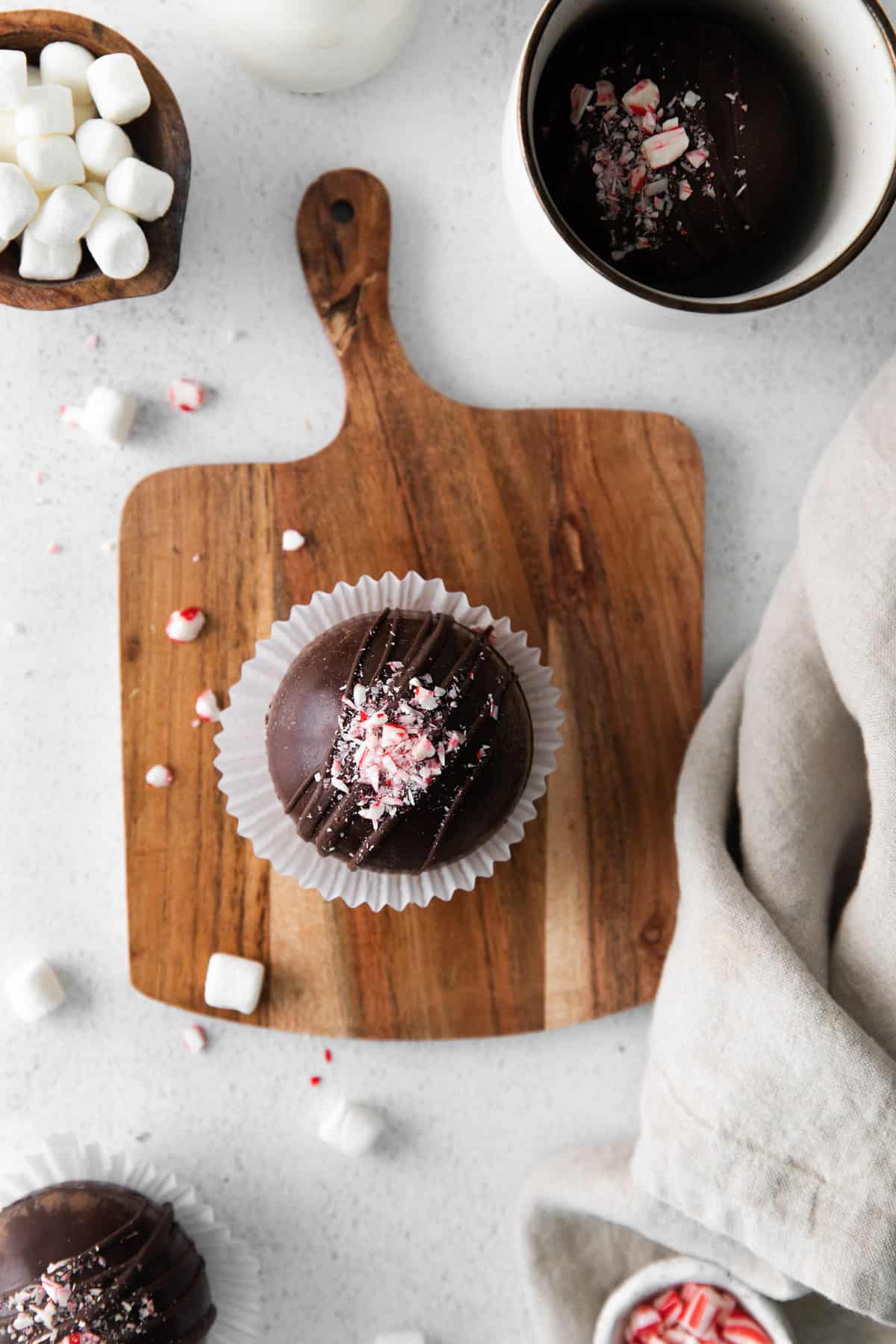 An overhead image of a peppermint candy cane hot cocoa bomb surrounded by marshmallows.
