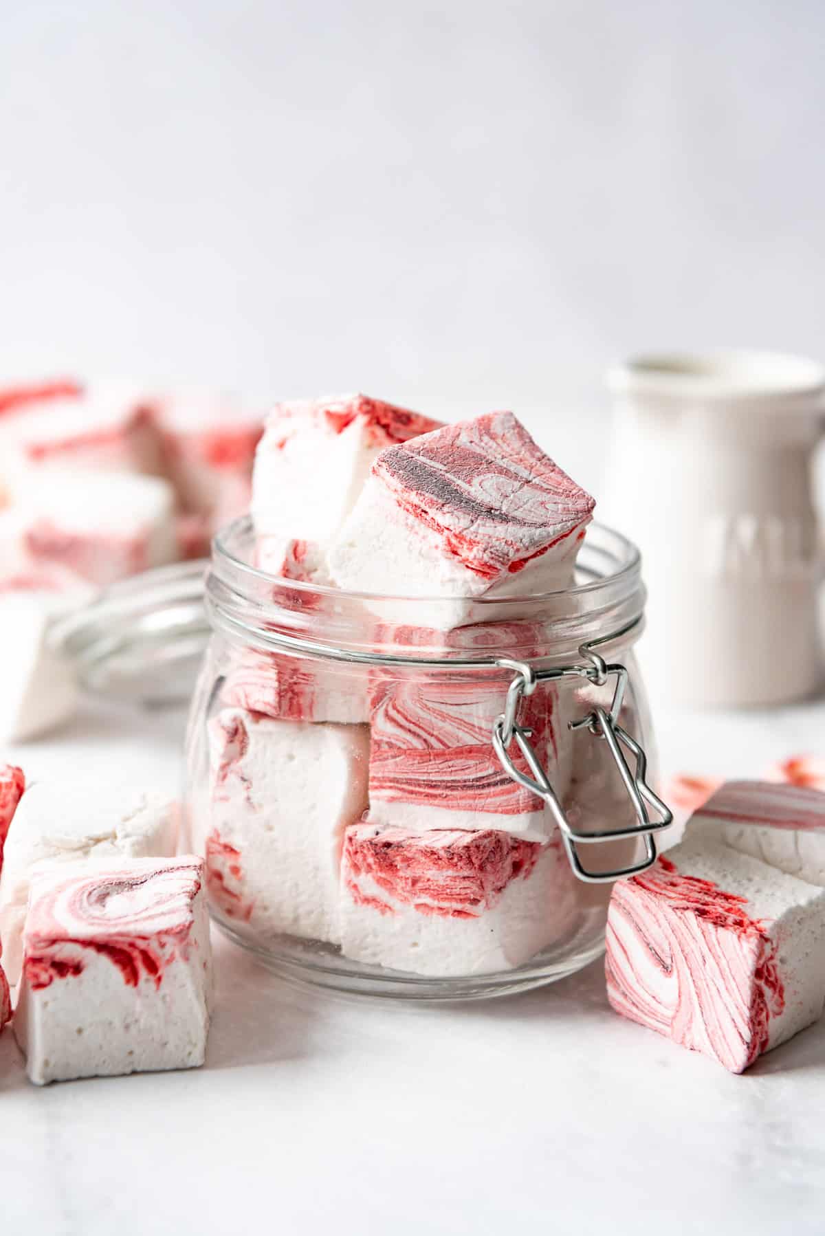 A glass jar filled with homemade peppermint marshmallow cubes.