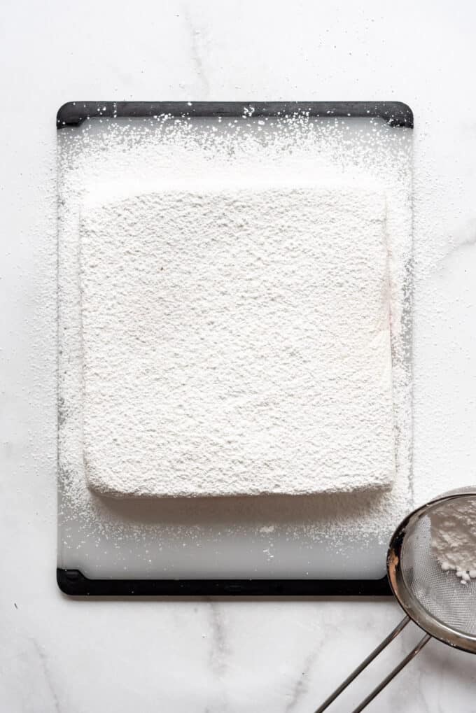Dusting a slab of marshmallow with powdered sugar and cornstarch.