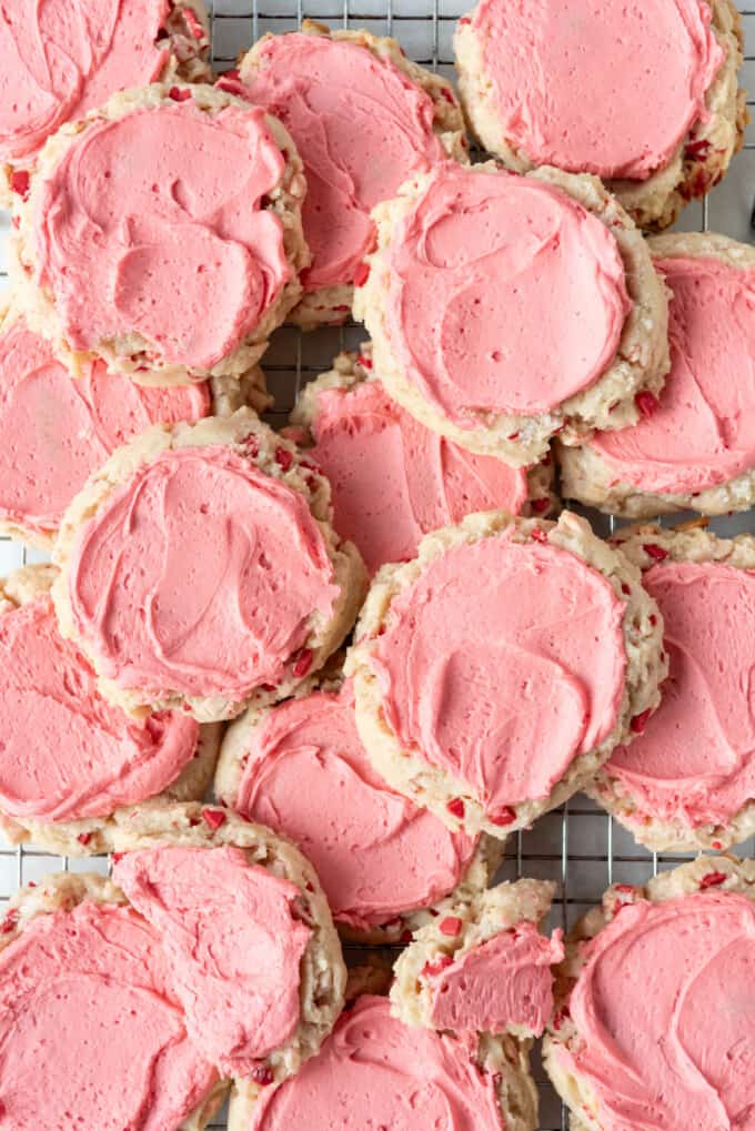 An overhead image of peppermint sugar cookies with pink frosting haphazardly arranged.