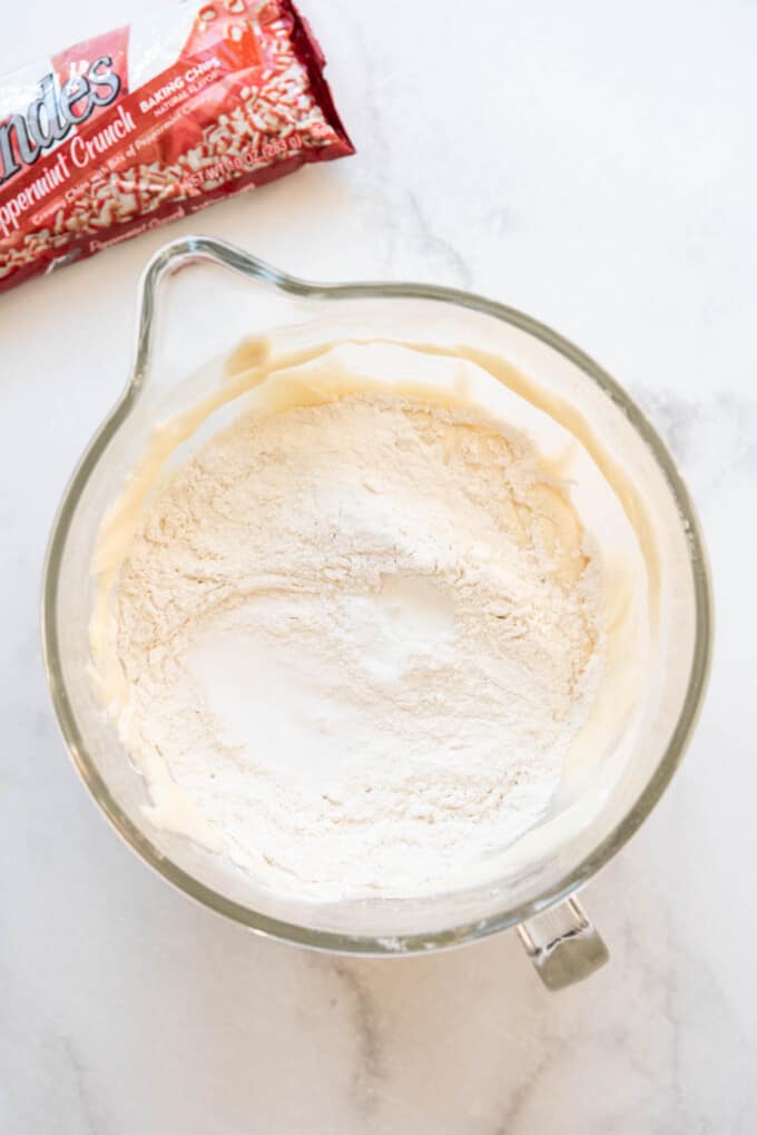 Adding dry ingredients to make swig peppermint sugar cookies.