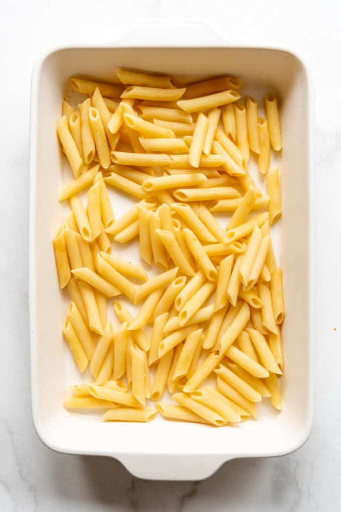 Cooked and drained penne pasta in a casserole dish.