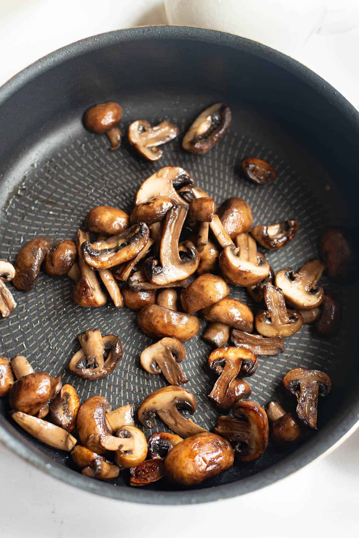 Mushrooms being sauteed in a pan.