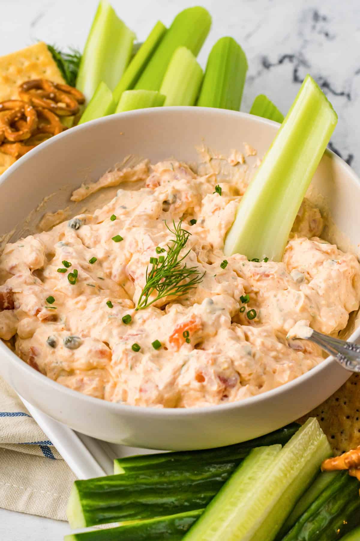 Smoked salmon dip in a white bowl with a stick of celery in it. 