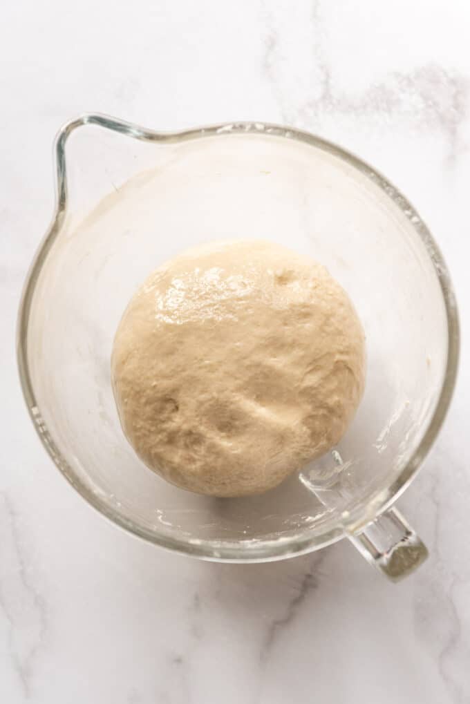 Bread dough that has been kneaded until smooth and is ready to rise in a greased bowl.