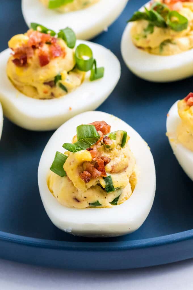 Classic deviled eggs with crumbled bacon and green onions sprinkled on top.