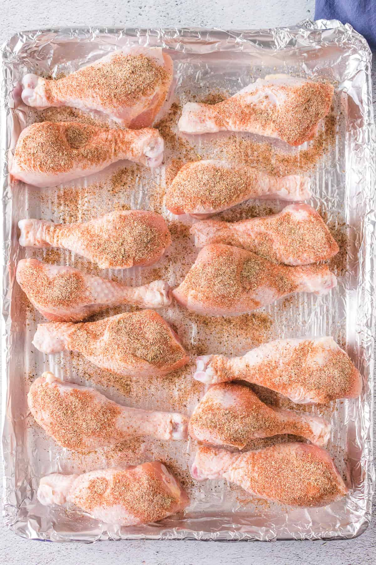 Chicken drumsticks on a baking sheet ready to go in the oven.