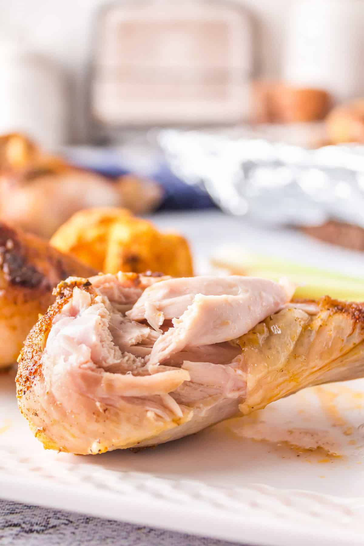 A juicy baked chicken drumsticks with a bite taken out of it.