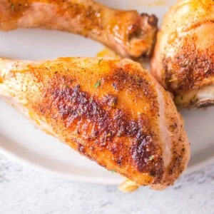 A baked chicken drumstick on a white plate.