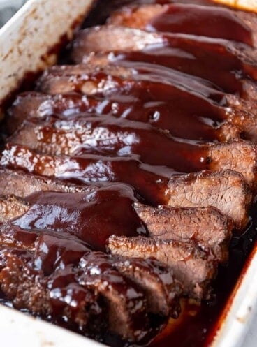 A large brisket made in the oven and sliced into pieces then topped with bbq sauce.
