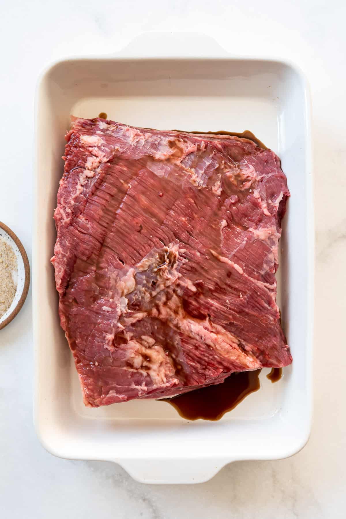 Moistening a large piece of beef brisket with worcestershire sauce.