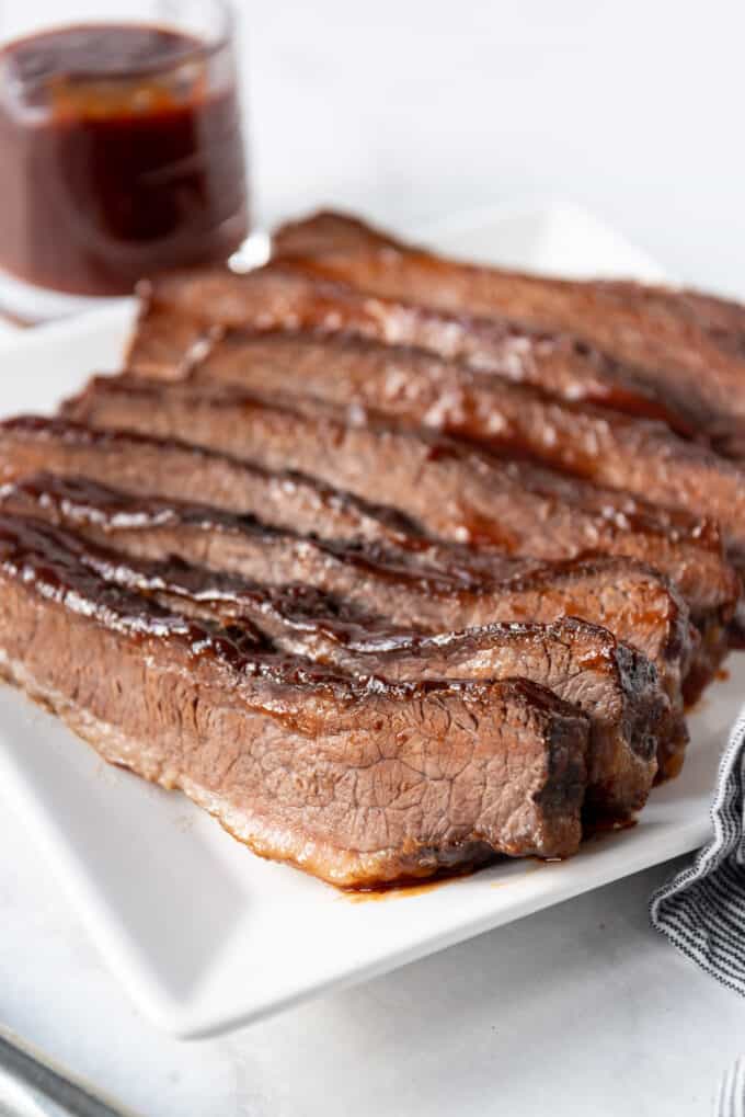 Rows of sliced beef brisket on a white plate.