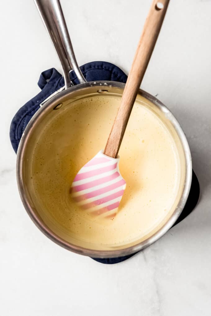 A spatula in a saucepan with a creamy sauce.