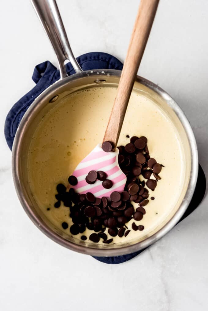 Adding chocolate to a creamy mousse base in a saucepan.