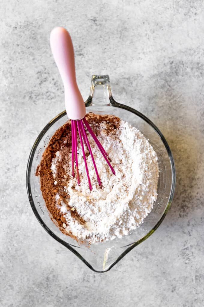 An image of cake flour and cocoa powder being whisked together for red velvet cake.