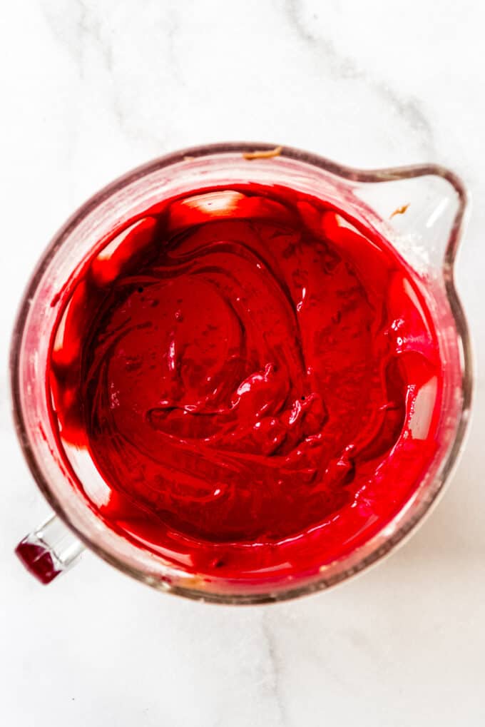 Red velvet cake batter in a large glass mixing bowl.