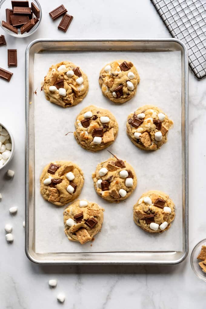 A baking sheet lined with parchment paper with eight s'mores cookies on it.
