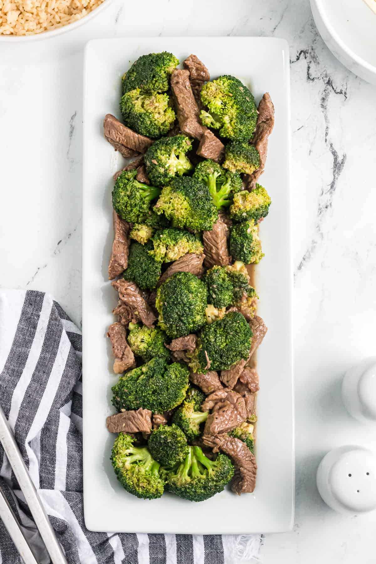 A large white rectangular serving plate filled with Chinese beef with broccoli.