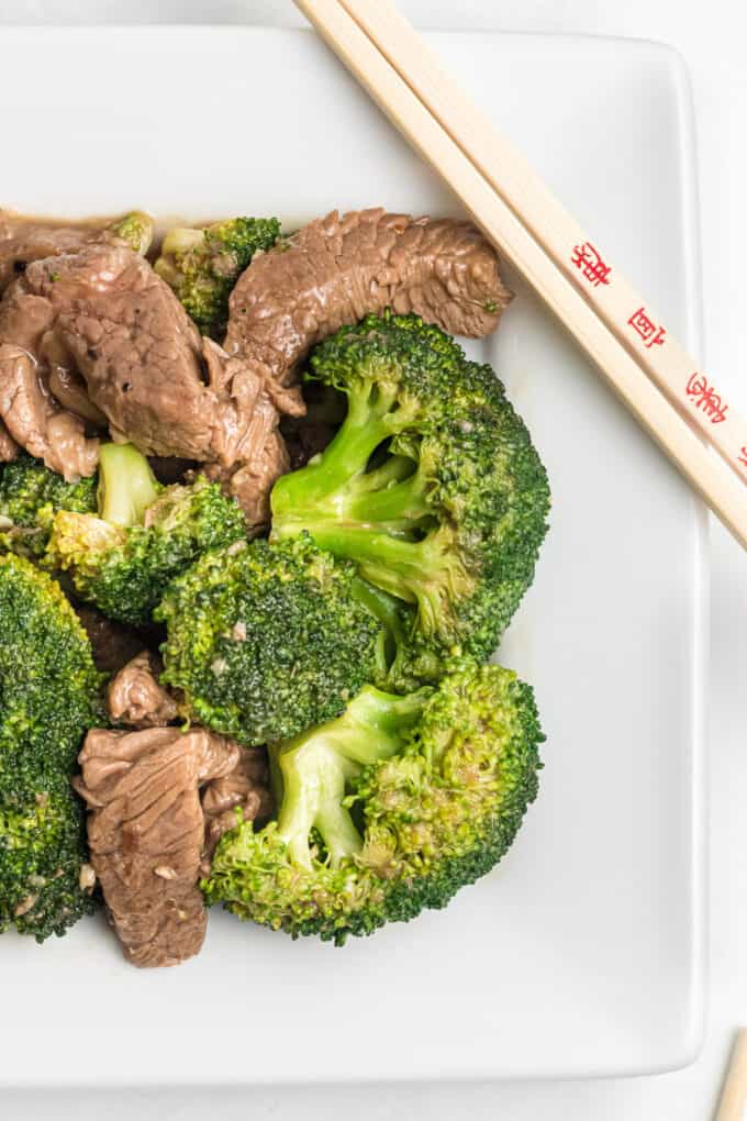 Chinese beef and broccoli on a white plate with chopsticks.